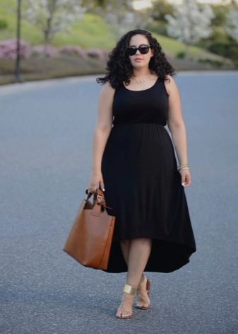 Vestido negro con una falda asimétrica completa con sandalias doradas y una bolsa marrón